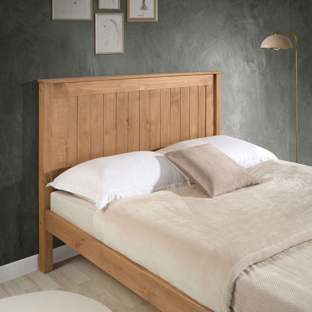 Wooden bed with beige bedding against a gray wall