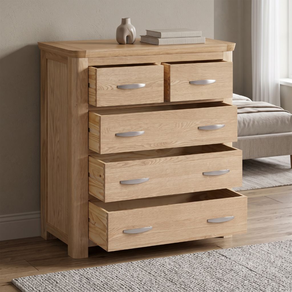 A light oak wood five-drawer chest of drawers with silver metal handles and sleek curved edges 