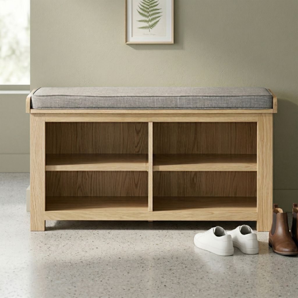 A light natural wood bench with a grey upholstered cushion on top and four open storage shelves underneath for storing shoes.