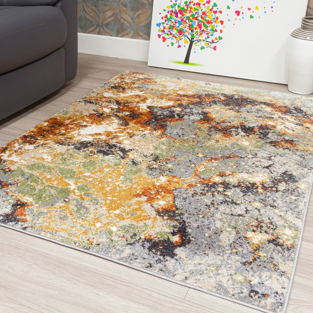 Multicolored abstract patterned rug on a wooden floor with a couch and wall art in the background.