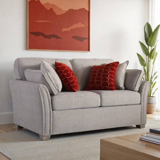 Natural sofa with red and natural pillows in a living room setting.