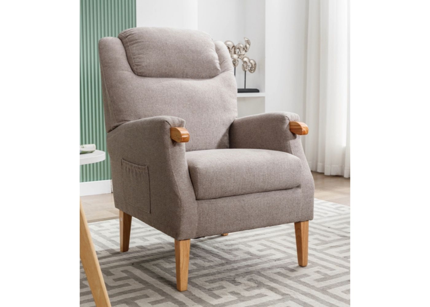 Beige upholstered armchair with wooden armrests and pocket on the side.